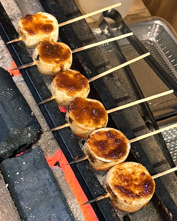 A row of king oyster mushrooms coated in a miso dengaku on a japanese style grill