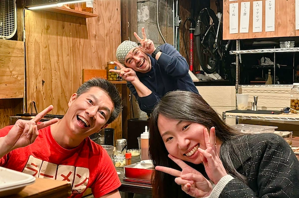 Three people smiling and holding up the peace sign